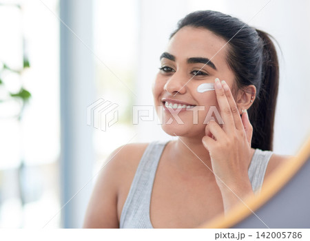 Beauty, cream and reflection of woman in mirror of bathroom for cosmetics, skincare or vitamin c. Face, lotion or dermatology and happy person with smile in home for antiaging wellness routine 142005786
