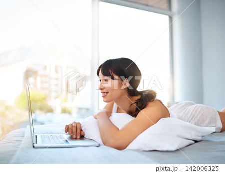 Woman, home and smile with laptop in bed for streaming movies and series on website. Female person, happy and online with technology for internet, communication and entertainment in bedroom. 142006325