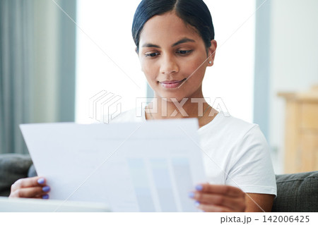 Woman, documents and reading with paperwork for finance, budget planning or expenses on sofa at home. Young female person with smile for daily schedule, pay slip or checking bills on house or assets 142006425