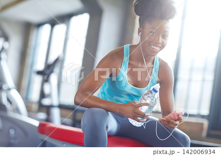 Smartphone, headphones and portrait of black woman in gym with water, fitness app or online subscription. Health, wellness and girl checking music playlist on phone with bottle, break and sports club Smartphone, headphones and portrait of black woman in gym with water, fitness app or online subscription. Health, wellness and girl checking music playlist on phone with bottle, break and sports club 142006934