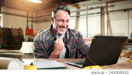Mature, carpenter and happy man with success on laptop for good news or in business workshop. Excited, male person or carpentry with smile, computer or fist pump for achievement in wood warehouse 142008810