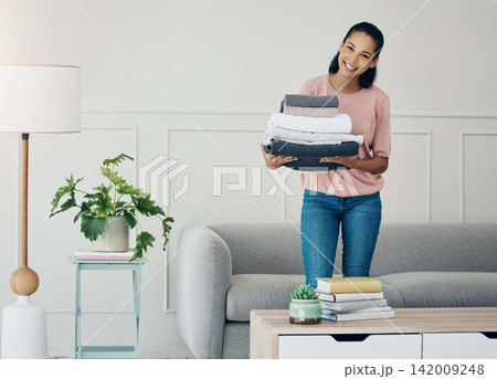 Woman, home and happy portrait with laundry, living room and towels for housekeeping or cleaning service. Hospitality, helping for apartment maintenance, washing or clean clothes for chores or job 142009248