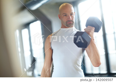Man, weight lifting and serious in gym for fitness with dumbbell, workout challenge and strong muscle. Bodybuilder, pro athlete and strength training with concentration and exercise for competition 142009507