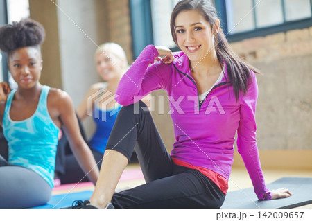 Portrait, yoga class and woman with smile in gym for wellness, body care and mindfulness. Female people, ready and collaboration with happiness for support, teamwork and workout at health club 142009657