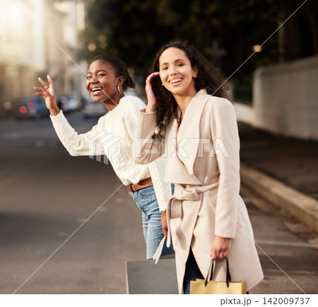 Women, city and calling for taxi after shopping with smile, happiness with sale on product. Female friends, together and hand sign with fashion in urban for car, transport or travel from sidewalk 142009737