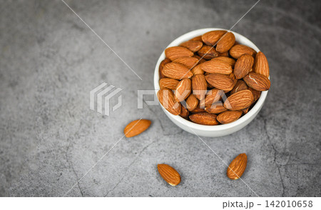 Almonds bowl on gray background / Close up almond nuts natural protein food and for snack Almonds bowl on gray background / Close up almond nuts natural protein food and for snack 142010658
