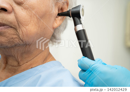 Otolaryngologist or ENT physician doctor examining senior patient ear with otoscope, hearing loss problem. Otolaryngologist or ENT physician doctor examining senior patient ear with otoscope, hearing loss problem. 142012429