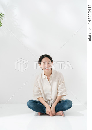 あぐらをかいて床に座る笑顔の女性 142015456