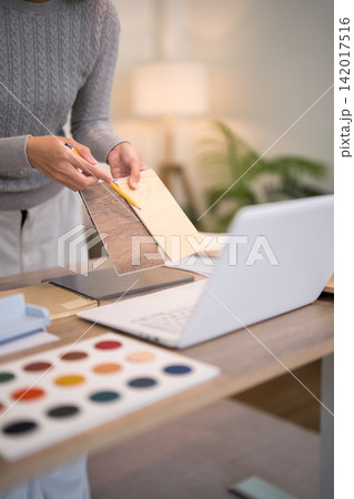 Asian furniture designer selecting wood finish samples holding color palette at creative studio workspace with copy space 142017516