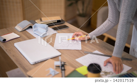 Asian furniture designer sketching technical drawing with yellow pencil on wooden workspace in home office with copy space Asian furniture designer sketching technical drawing with yellow pencil on wooden workspace in home office with copy space 142017519
