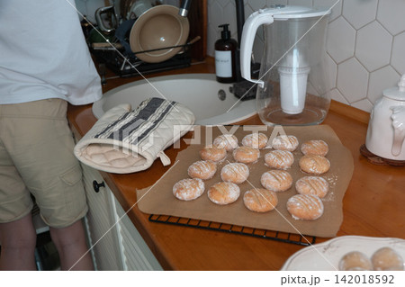 Freshly baked almond cookies dusted with powdered sugar cool on baking paper beside kitchen sink. Home baking, homemade dessert, confectionery, pastry, baking process, family recipe, comfort food Freshly baked almond cookies dusted with powdered sugar cool on baking paper beside kitchen sink. Home baking, homemade dessert, confectionery, pastry, baking process, family recipe, comfort food 142018592