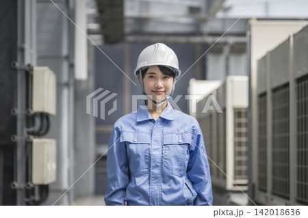 カメラ目線で微笑む作業服を着た若い女性 142018636