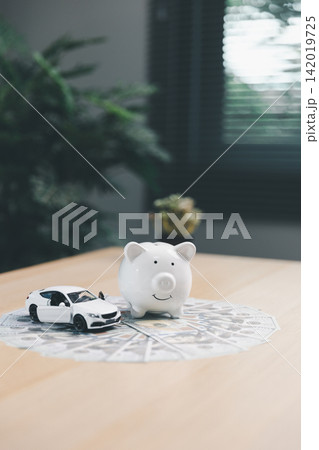 Piggy bank and miniature car on cash bills, symbolizing saving money for a vehicle, auto loan approval, car purchase, insurance, and financial planning. Piggy bank and miniature car on cash bills, symbolizing saving money for a vehicle, auto loan approval, car purchase, insurance, and financial planning. 142019725