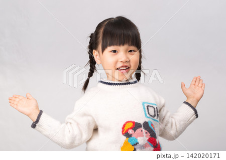Cheerful little girl in white winter sweater spreading arms with an open friendly smile. Cheerful little girl in white winter sweater spreading arms with an open friendly smile. 142020171