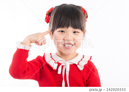 Cute Asian preschool girl in red sweater pointing at her ears with fingers smiling at camera. Cute Asian preschool girl in red sweater pointing at her ears with fingers smiling at camera. 142020333