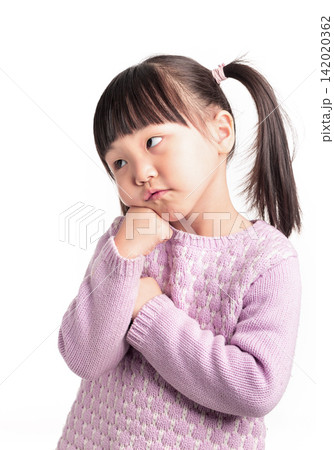 Adorable little girl with pigtails holding her chin and looking sideways on white background. 142020362
