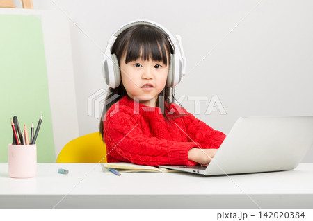 Diligent Asian schoolgirl typing on laptop keyboard during online elementary class. Diligent Asian schoolgirl typing on laptop keyboard during online elementary class. 142020384