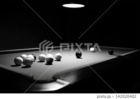 Billiard table set for a game in dim lighting with overhead illumination Billiard table set for a game in dim lighting with overhead illumination 142020482