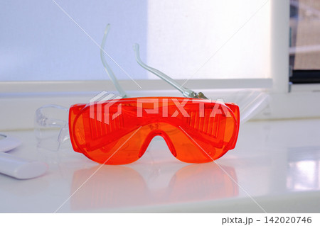 Orange dental safety glasses for eye protection during professional treatment in modern dental clinic close up medical protective equipment photography Orange dental safety glasses for eye protection during professional treatment in modern dental clinic close up medical protective equipment photography 142020746
