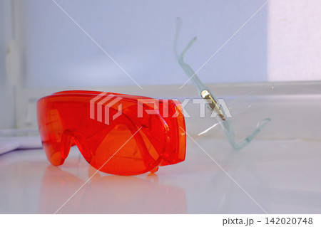 Orange dental safety glasses for eye protection during professional treatment in modern dental clinic close up medical protective equipment photography Orange dental safety glasses for eye protection during professional treatment in modern dental clinic close up medical protective equipment photography 142020748
