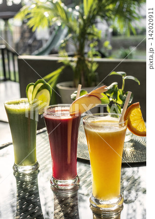 mixed fresh fruit juice glasses on outdoor garden cafe table in sunny summer day mixed fresh fruit juice glasses on outdoor garden cafe table in sunny summer day 142020911