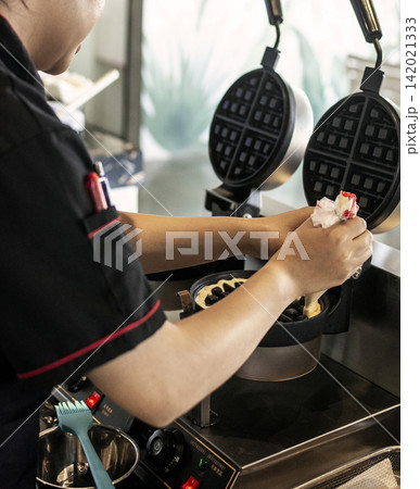 kitchen staff making fresh waffles in professional modern waffle cooking machine kitchen staff making fresh waffles in professional modern waffle cooking machine 142021333