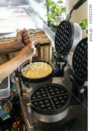 kitchen staff making fresh waffles in professional modern waffle cooking machine kitchen staff making fresh waffles in professional modern waffle cooking machine 142021336