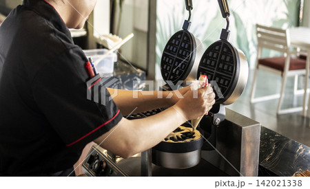 kitchen staff making fresh waffles in professional modern waffle cooking machine kitchen staff making fresh waffles in professional modern waffle cooking machine 142021338