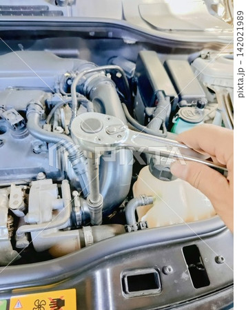 整備工場でラチェットレンチを使いエンジンルームの点検修理を行う整備士の手元 整備工場でラチェットレンチを使いエンジンルームの点検修理を行う整備士の手元 142021989