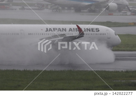 雨の滑走路に着陸する旅客機　エンジンの逆噴射の水煙　 142022277