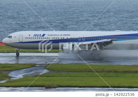 雨の滑走路に着陸する旅客機 エンジンの逆噴射の水煙 雨の滑走路に着陸する旅客機 エンジンの逆噴射の水煙 142022536