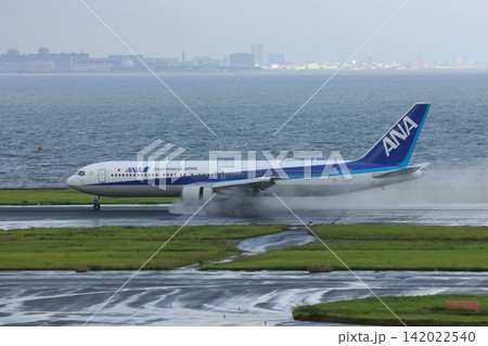 雨の滑走路に着陸する旅客機 エンジンの逆噴射の水煙 雨の滑走路に着陸する旅客機 エンジンの逆噴射の水煙 142022540