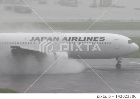 雨の滑走路に着陸する旅客機 エンジンの逆噴射の水煙 雨の滑走路に着陸する旅客機 エンジンの逆噴射の水煙 142022586
