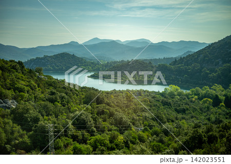 Lake in a lush valley with dense greenery surrounding it Lake in a lush valley with dense greenery surrounding it 142023551