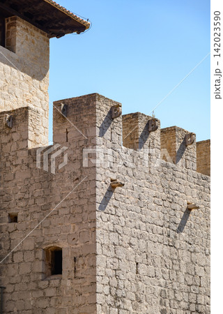A detailed high-angle photograph of an ancient stone fortress wall under a clear blue sky A detailed high-angle photograph of an ancient stone fortress wall under a clear blue sky 142023590