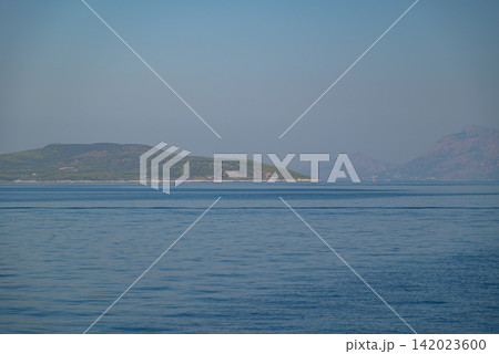 A serene seascape with a large verdant island rising from deep blue water A serene seascape with a large verdant island rising from deep blue water 142023600