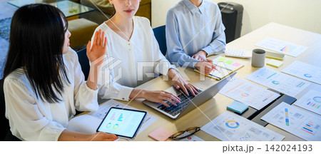 会議でタブレットとノートPCを操作する女性たち 142024193