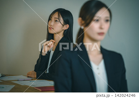 会議で資料を見ながら真剣に検討するビジネスウーマンたち 会議で資料を見ながら真剣に検討するビジネスウーマンたち 142024246