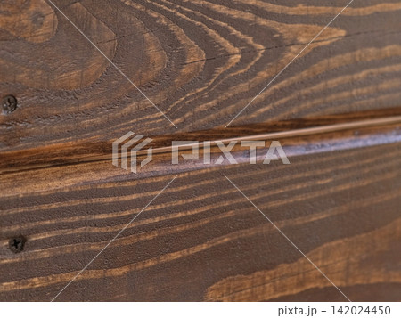 Brown oil for protection of wood by staining. Painting fence for protecting and pests. Woodworker applying finish to pine board box. Repairman varnishing with brush wooden fencing wall plank surface. 142024450