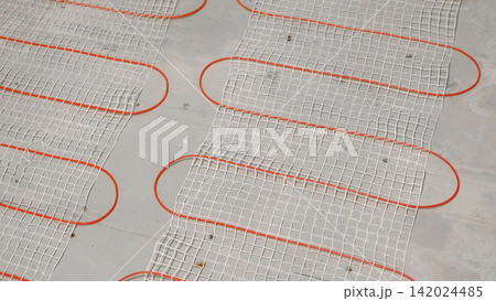 Electric Heating Mat Installing in the Tile Adhesive. Underfloor Dual Core Fiberglass Mesh Mat. Warm Floor Heating System. Warming. Worker Applying Concrete Mortar for Warm Floor. Renovation work. 4K 142024485