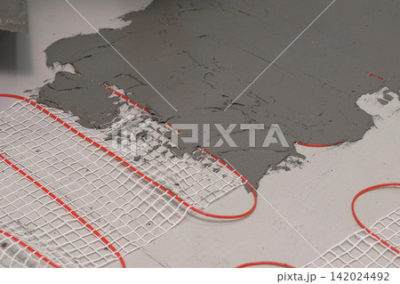 Electric Heating Mat Installing in the Tile Adhesive. Underfloor Dual Core Fiberglass Mesh Mat. Warm Floor Heating System. Warming. Worker Applying Concrete Mortar for Warm Floor. Renovation work. 4K Electric Heating Mat Installing in the Tile Adhesive. Underfloor Dual Core Fiberglass Mesh Mat. Warm Floor Heating System. Warming. Worker Applying Concrete Mortar for Warm Floor. Renovation work. 4K 142024492