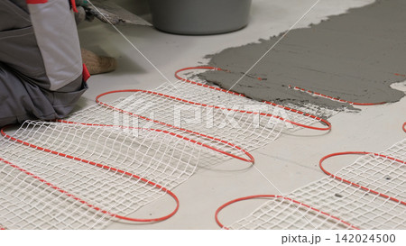 Electric Heating Mat Installing in the Tile Adhesive. Underfloor Dual Core Fiberglass Mesh Mat. Warm Floor Heating System. Warming. Worker Applying Concrete Mortar for Warm Floor. Renovation work. 4K 142024500