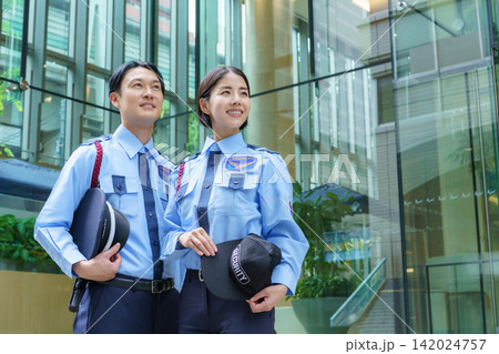 オフィスビルの前に立つ若い日本人男性警備員と女性警備員のポートレート オフィスビルの前に立つ若い日本人男性警備員と女性警備員のポートレート 142024757