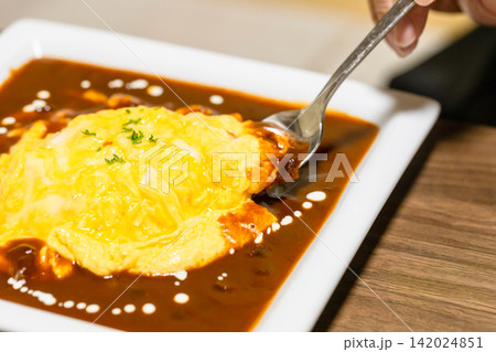 とろとろオムライスにデミグラスソースがかかっている　スプーンで食べようとしている 142024851