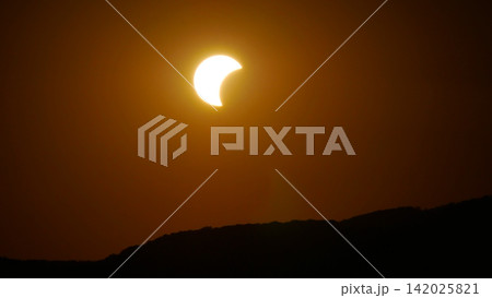 Partial solar eclipse above mountain silhouette - glowing crescent sun, astronomy, nature and cosmic phenomenon concept. 142025821