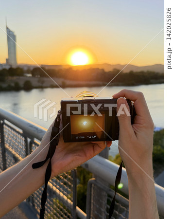 Hands of a man taking photos of solar eclipse with photo camera. 142025826