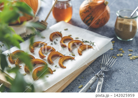 Autumn vegetarian food recipe. Baked mini pumpkin with  herbs, and honey on a wooden board over grey table. 142025959