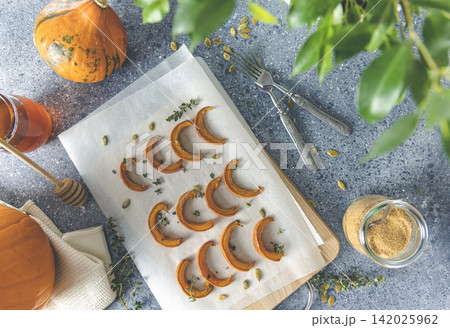 Autumn vegetarian food recipe. Baked mini pumpkin with herbs, and honey on a wooden board over grey table top view Autumn vegetarian food recipe. Baked mini pumpkin with herbs, and honey on a wooden board over grey table top view 142025962