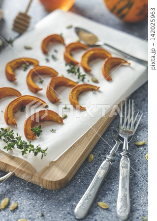 Autumn vegetarian food recipe. Baked mini pumpkin with  herbs, and honey on a wooden board over grey table. 142025963
