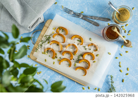 Autumn vegetarian food recipe. Baked mini pumpkin with  herbs, and honey on a wooden board over light blue table top view. 142025968
